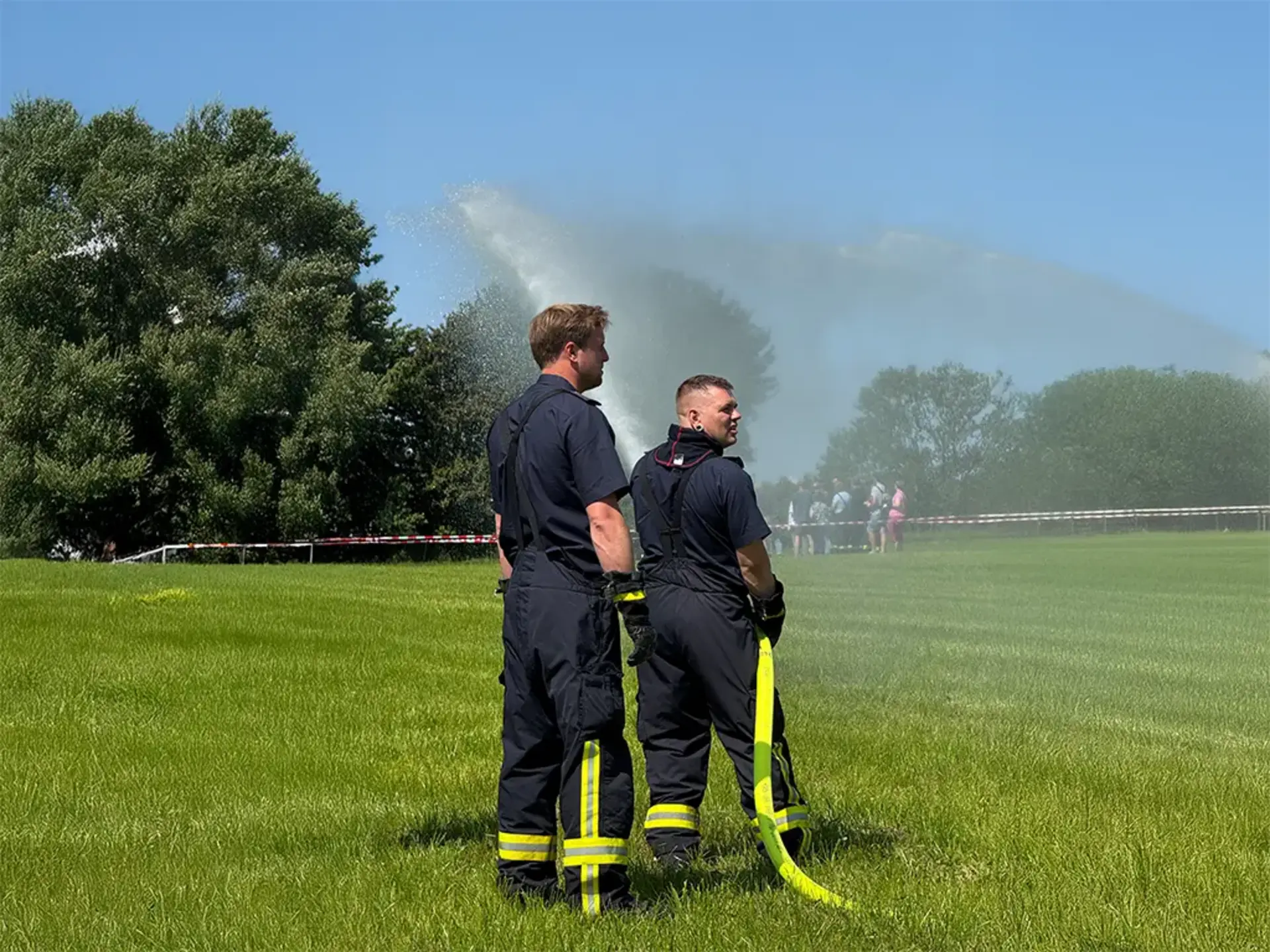 Zwei Feuerwehrmänner halten einen Wasserschlauch