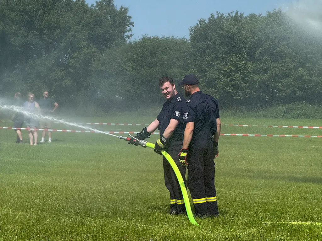 Eine Feuerwehrfrau und ein Feuerwehrmann reden mit dem Wehrführer