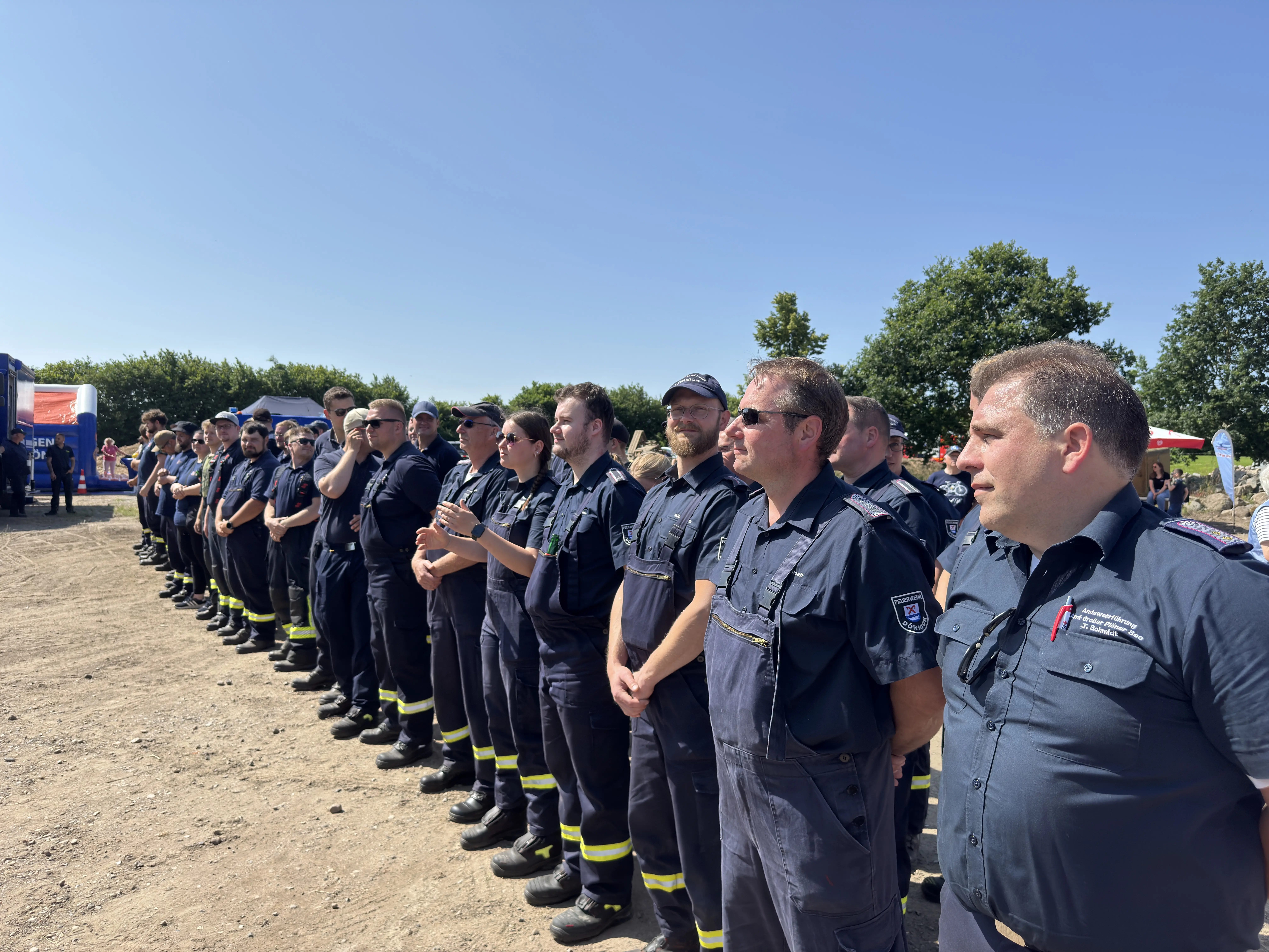 7 Feuerwehrmänner, 2 davon stehen zwischen den Tischen und der eine zeigt einen Daumen hoch