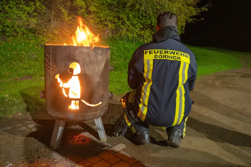 Ein Feuerwehrmann kümmert sich um das Feuer in der Feuertonne
