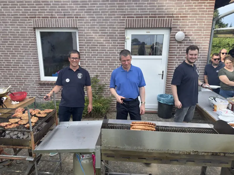 3 Feuerwehrleute stehen hinter den Gill und verorgen die Gäste mit Wurst, Fleisch und Salaten