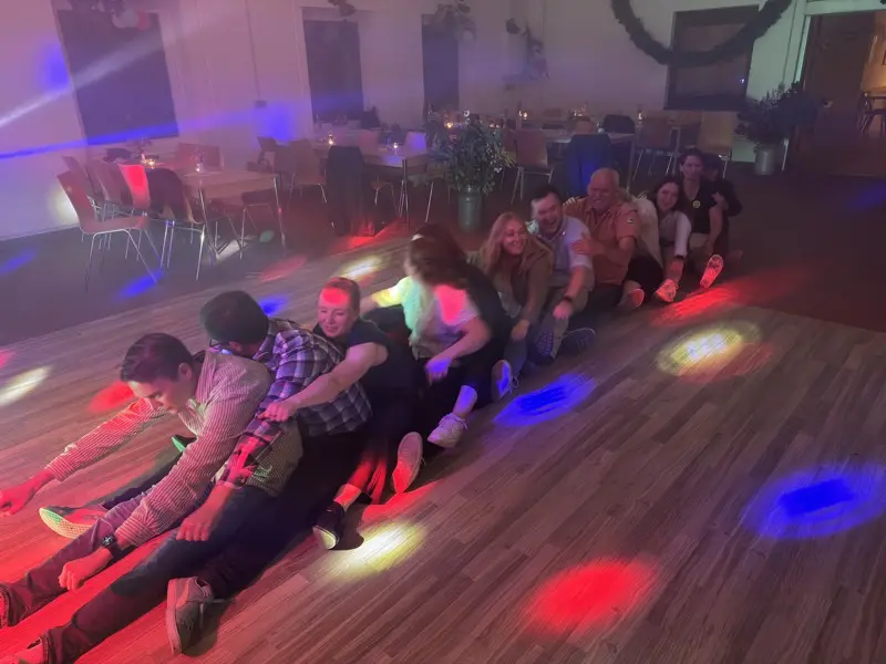 Eine Gruppe sitzt hintereinander auf dem Boden und tut so als würden sie rudern